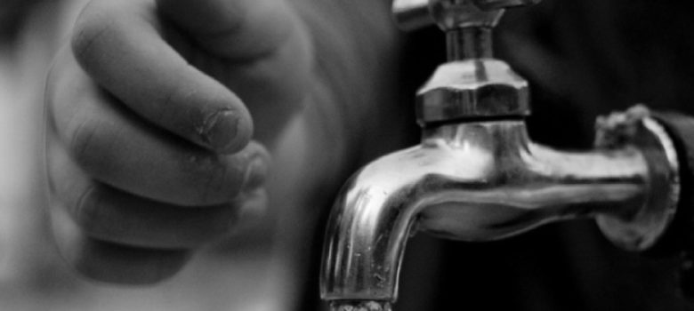 small hand reaching to turn off the water tap to conserve water